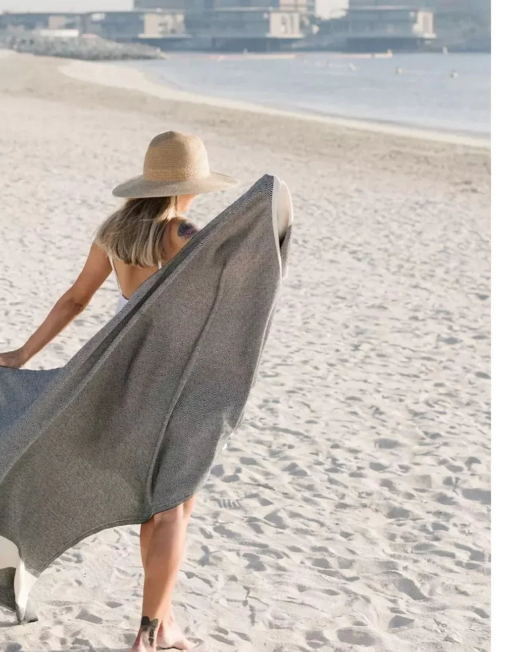 Frau mit grauem waschbarem Bambusteppich am Strand, ideal für Outdoor & Strandurlaub