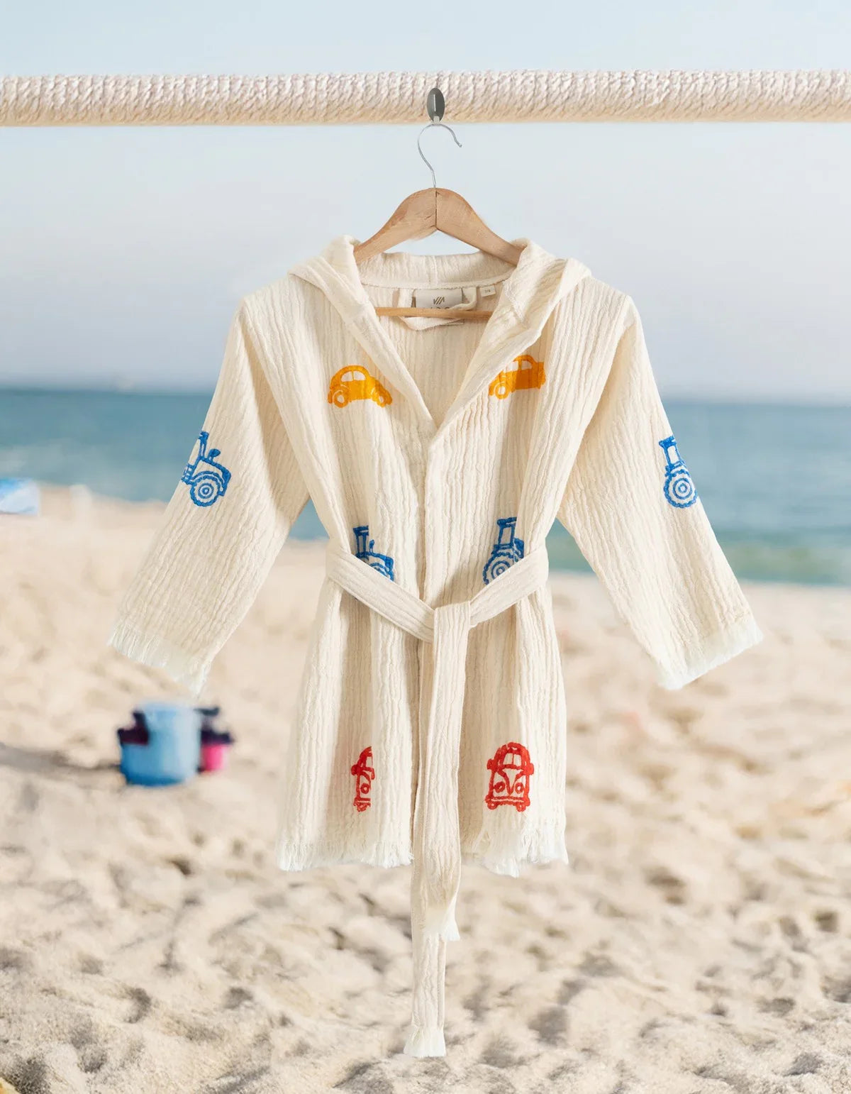 Kinderbademantel mit bunten Auto- und Traktormotiven am Strand